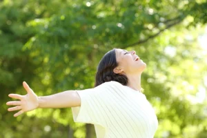 A young woman with her arms outstretched, surrounded by healthy trees in her yard in Alton, IL.